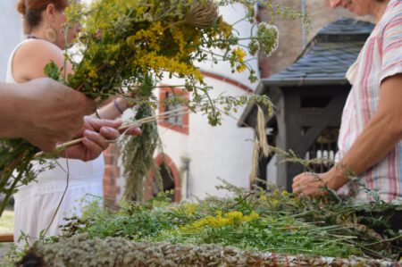 Das Bild zeigt Teilnehmerinnen beim Kräuterbuschenbinden auf Schloss Rochsburg 2023.