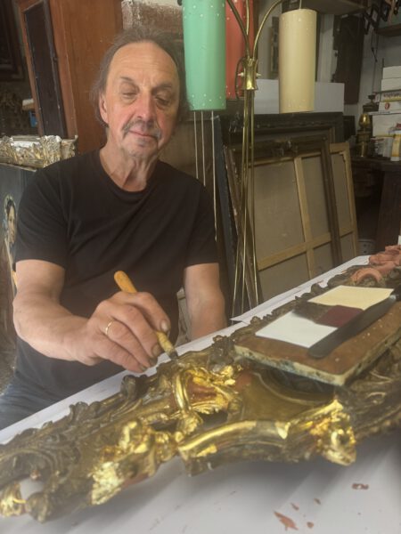 Restaurator Thomas Heinicke bearbeit einen goldenen historischen Bilderrahmen und verleiht diesem seinen alten Glanz zurück.